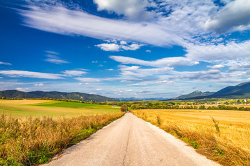 Road around fields through rural landscape in sunny summer day. Rajec Valley area, Slovakia, Europe.