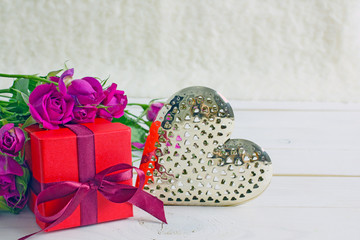 Valentine's Day greeting card. A bouquet of red roses and a beautiful shiny metal heart on a white table, copy space.