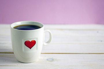 Breakfast for Valentine's Day. White cup of tea with a red heart on it on a wooden light table. Copy space
