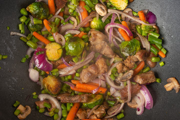 Vegetables fried with meat, in a pan close-up, culinary background