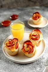 Muffins roses from puff pastry with ham and cheese on a light background.