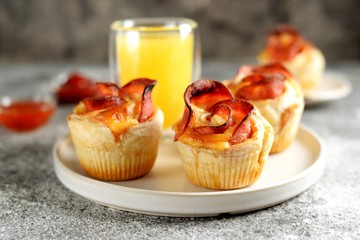 Muffins roses from puff pastry with ham and cheese on a light background.