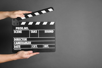 Fototapeta premium Woman holding clapperboard on dark grey background, closeup with space for text. Cinema production