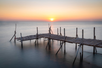 Fototapeta na wymiar Old wooden bridge at sea in the morning