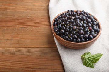 Fresh black currant in wooden bowl on wooden background. top view.