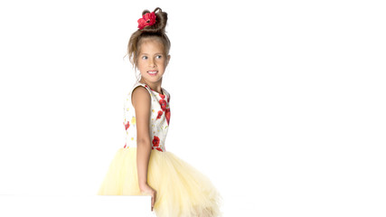 A little girl is looking from behind an empty banner.