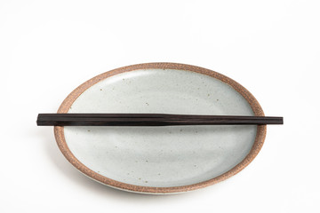 A Pair Of Chopsticks With Stoneware Plate