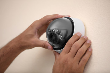 Technician installing CCTV camera on wall, closeup