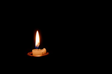 A candle burning in the dark. The candle almost burned out.