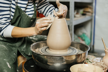 Hands of potter making clay pot on potter's wheel