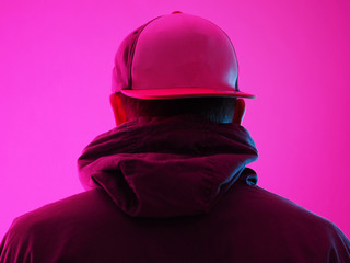 Neon light man in hoody. Bright colorful light effects. Back view.