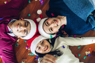 Portrait of happy family father and mother with daughter in santa hats having fun look at camera and enjoying spending time together in christmas time at home