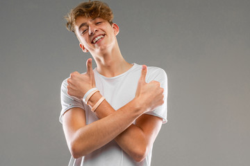 Young caucasian man in white t-shirt posing and gesticulating on camera isolated on grey background