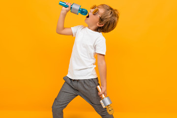 boy enjoys singing into a microphone on an orange background