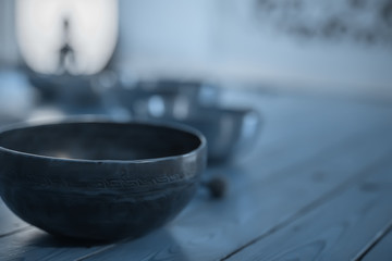 Singing bowls on the wooden floor, blue toned.