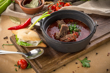 Red beetroot soup borshch with beef, wheat bun and sour cream on wooden table