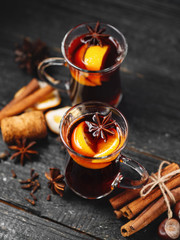 Traditional winter and Christmas hot drink mulled wine on a wooden table . With cinnamon, anise, tangerine