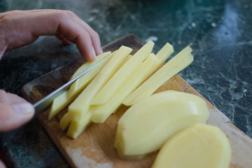 closeup of a hand cutting a potato with a knife