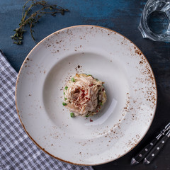 Chicken salad with mushrooms, onion, green peas, cucumber and eggs on a plate. Top view