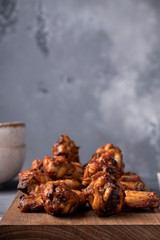 Tasty roasted chicken wings on wooden board with copy space