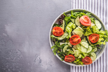 Tasty salad with mix of fresh greens, cucumbers and  tomatoes. Diet food concept. Top view with copy space