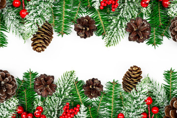 Christmas frame decorated with snowy fir branches, pine cones and red Holly Berries on white...