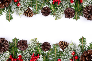 Christmas frame decorated with snowy fir branches, pine cones and red Holly Berries on white background. New Year traditional background. Winter holidays decoration design. Part of set. 
