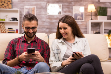 Cheerful young couple laughing together while sitting on sofa
