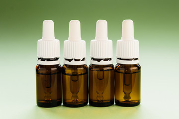 cosmetology, skin care, a row of glass bottles with pipettes and hyaluronic acid inside on a green...