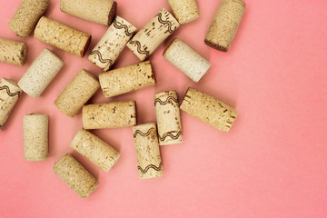Assorted wine corks from white and red vine on pink paper background with empty space for your text. Top view and flat lay.
