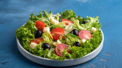 Dieting healthy salad with greens, cherry tomatoes. onion, cheese and black olives. Concept of  healthy vegetarian meal.