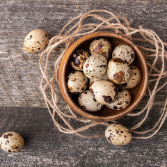 Quail eggs in wooden bowl over dark old wooden background. Top view