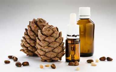 two pine cones with pine nuts and glass bottles on a white background, close-up