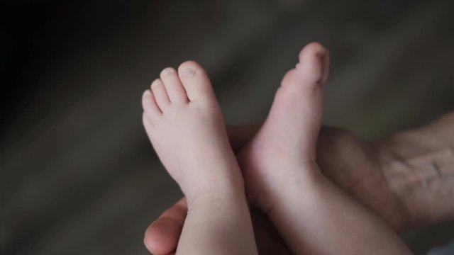 Baby feet in mother hands. Tiny Newborn Baby's feet. Caring mother with baby,