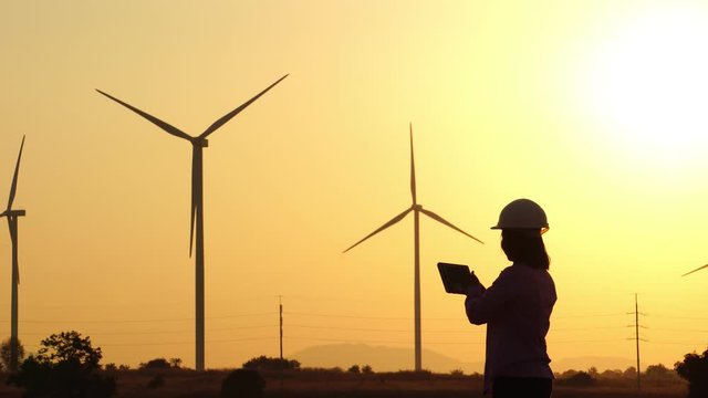 Woman engineer with hard hat against wind turbine footage 4K