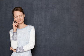 Portrait of happy young woman smiling and touching temple with finger