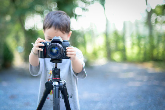  boy is photographer holds a camera on tripod and takes photo 