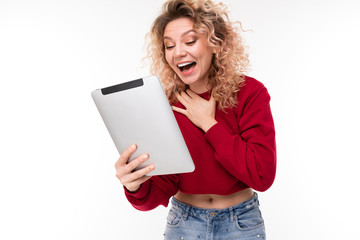 European curly blonde girl with on tablet on a white wall.