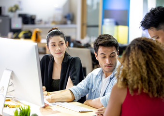 Working together on project. Three young business colleagues working on computer