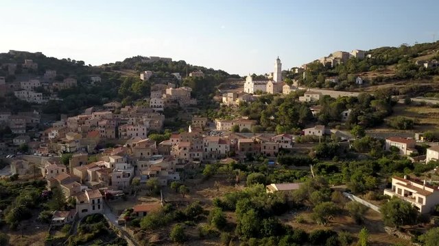 Aerial drone side flight footage in the afternoon time at summer season of Corbara village in the Corse island, France.