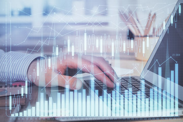 Double exposure of businessman's hands with laptop and stock market graph background. Concept of research and trading.