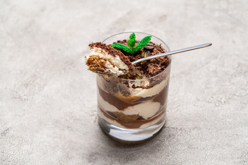 Classic tiramisu dessert in a glass cup on concrete background