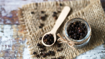 Selective focus. Macro. Black pepper peas. Black pepper in a jar and in a wooden spoon.
