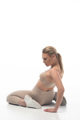 Obraz premium back view of sexy blonde girl in beige leggings twerking on floor isolated on white