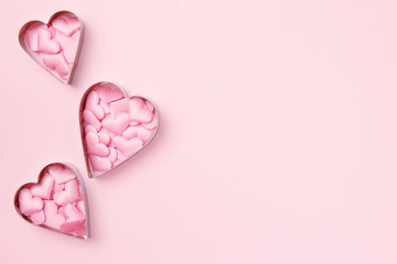 3 cutters cookies in heart shape with confetti on pastel pink background. Concept Valentine's card. Top view, copy space for text.