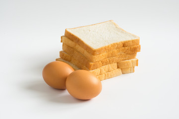 Eggs with stack of white breads on white .