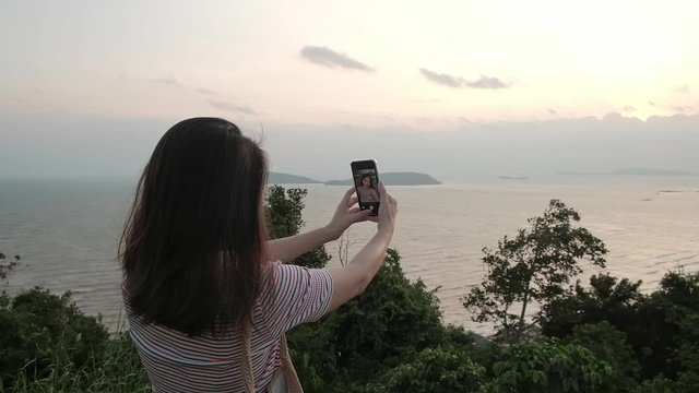 Woman taking selfie with beach view in the morning.