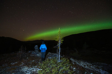 Northern lights/aurora borealis and starry sky from outdoors in the middle of the forest. Girl...