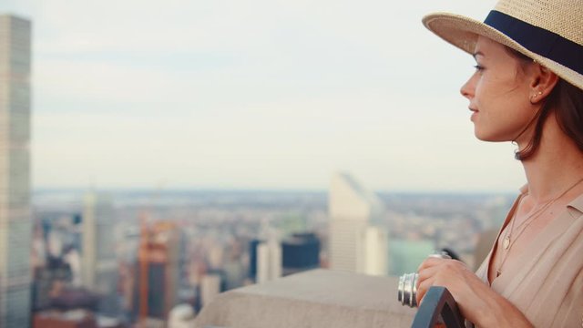 Attractive girl with a retro camera on the roof of New York skyscraper