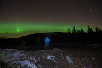 Northern lights/aurora borealis and starry sky from outdoors in the middle of the forest. Girl...